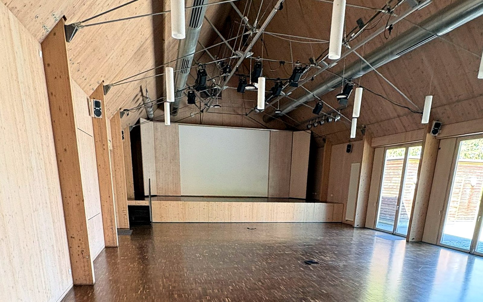 Großer Saal mit Bühne, Projektionsfläche und freier Fläche für Vorträge, Demos und Ausstellerformate